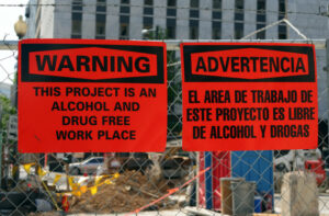 English and Spanish warning signs at job site saying This Project is an alcohol and drug free work place