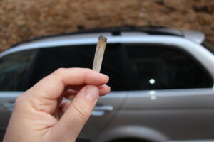 Person holding a joint with a minivan in the backgroud